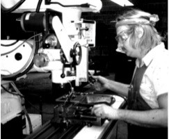 Machinist using a manual vertical mill to machine the body of a head (1986)
